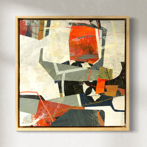 A framed abstract collage artwork featuring geometric shapes in shades of red, orange, gray, and white, displayed on a wall.