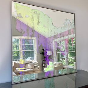 An original fine art mirror by Alina B rests on a wood dresser. 