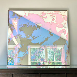 A fine art mirror rests on a wood dresser.