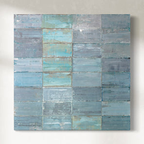 Square original painting with horizontal blue and gray stripes on metal plates hanging on a white wall.