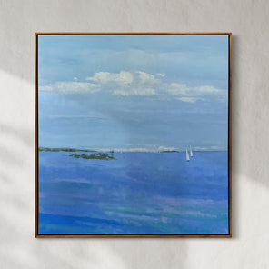 Framed painting of a blue landscape with clouds and sailboats on a gray wall.