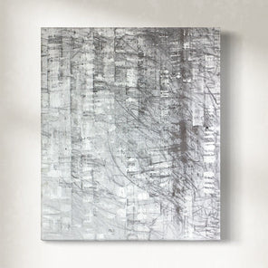 Abstract painting with gray and white patterns hanging on a light gray wall.