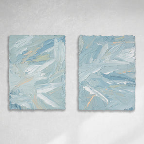 A pair of thickly painted paintings in teal, sea foam green, celadon, white and hints of orange and yellow by Teodora Guererra hang on a white wall. The two painting are like wall sculptures.