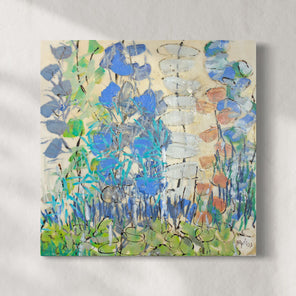 A green and blue abstracted encaustic floral painting hangs on a white wall.