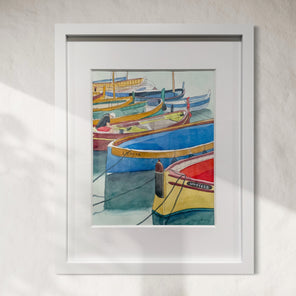 Framed artwork of colorful boats on a white wall