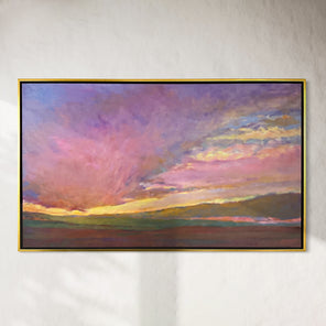 Framed painting of a colorful sunset over a landscape on a white wall.